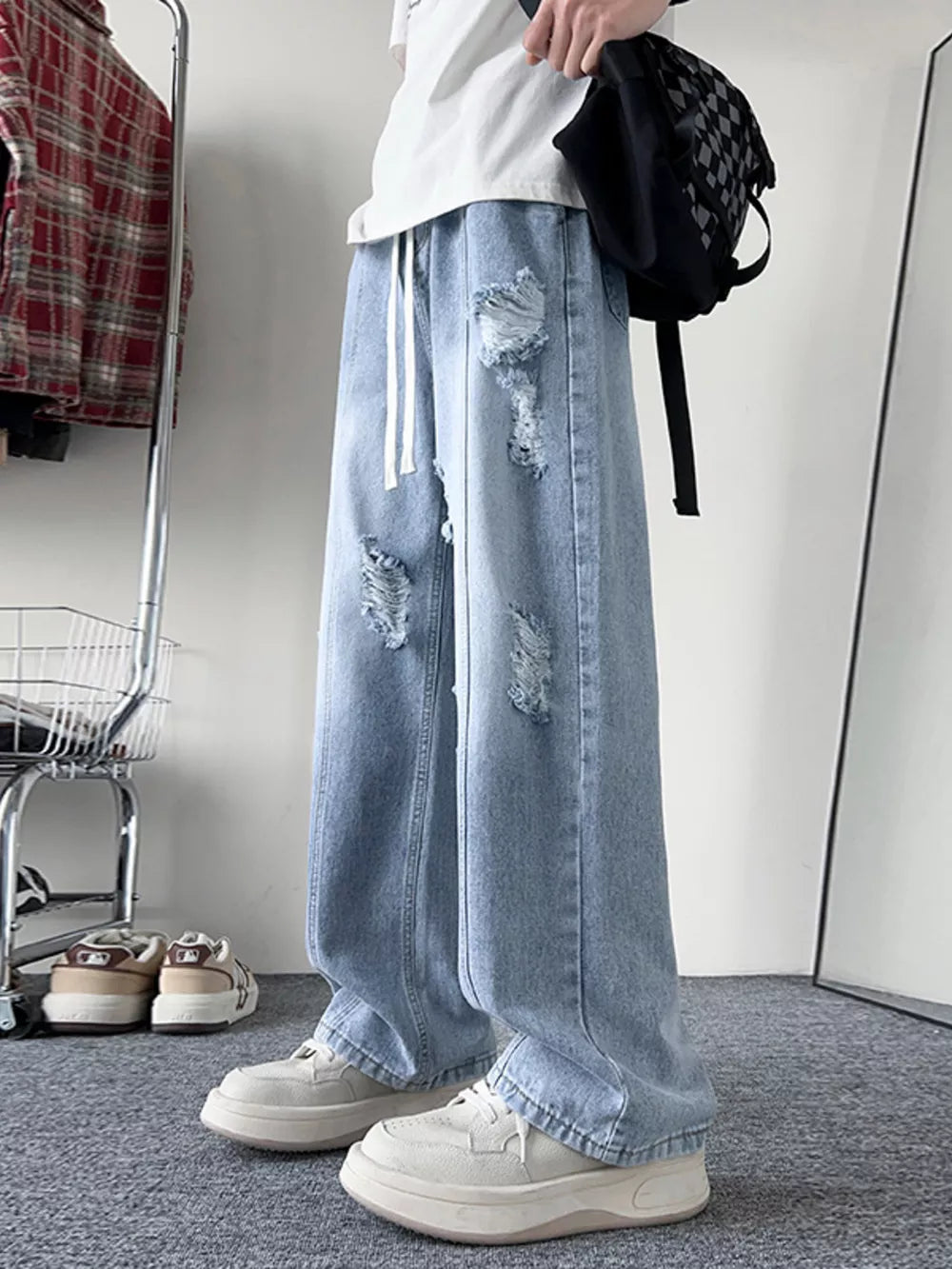 Light blue distressed wide-leg jeans with drawstring and ripped details.