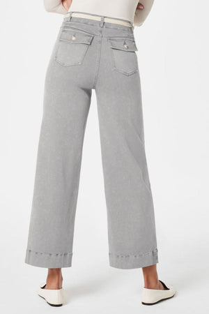 Wide-leg utility denim trousers in light gray with buttoned back pockets and a white belt.