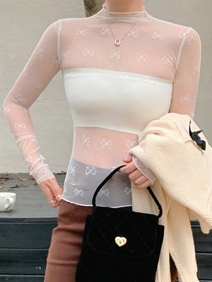 Sheer white mesh shirt with all-over bow print, mock neck, and long sleeves.