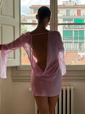 Pink chiffon backless mini dress with draped detail and long sleeves.