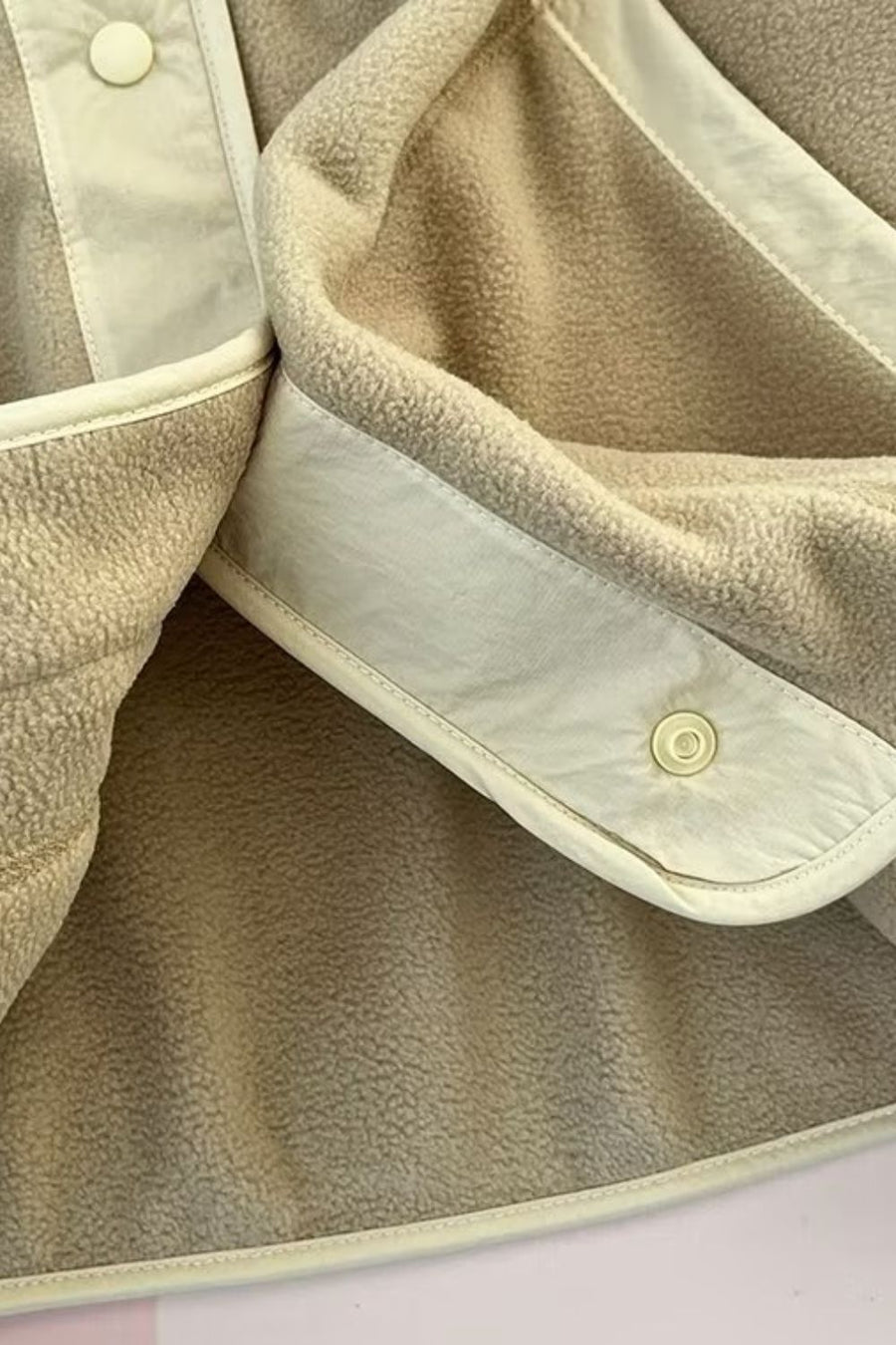 Tan fleece bomber jacket with contrast trim and snap button detail.