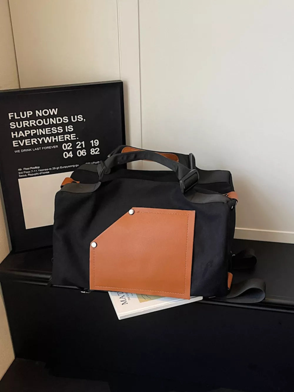 Black nylon crossbody bag with contrast tan pocket and strap detail