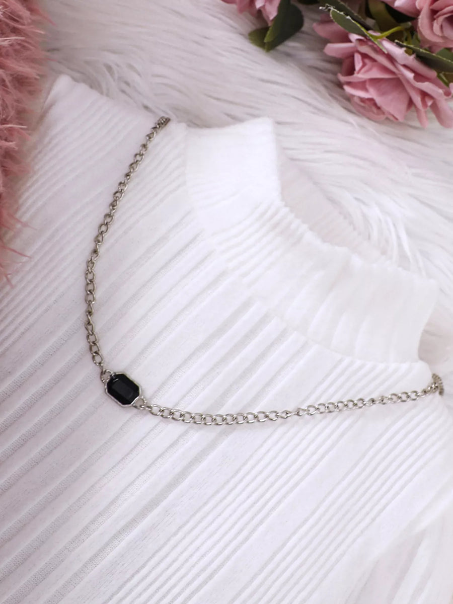 White ribbed dress with a silver chain necklace featuring a black gem detail.