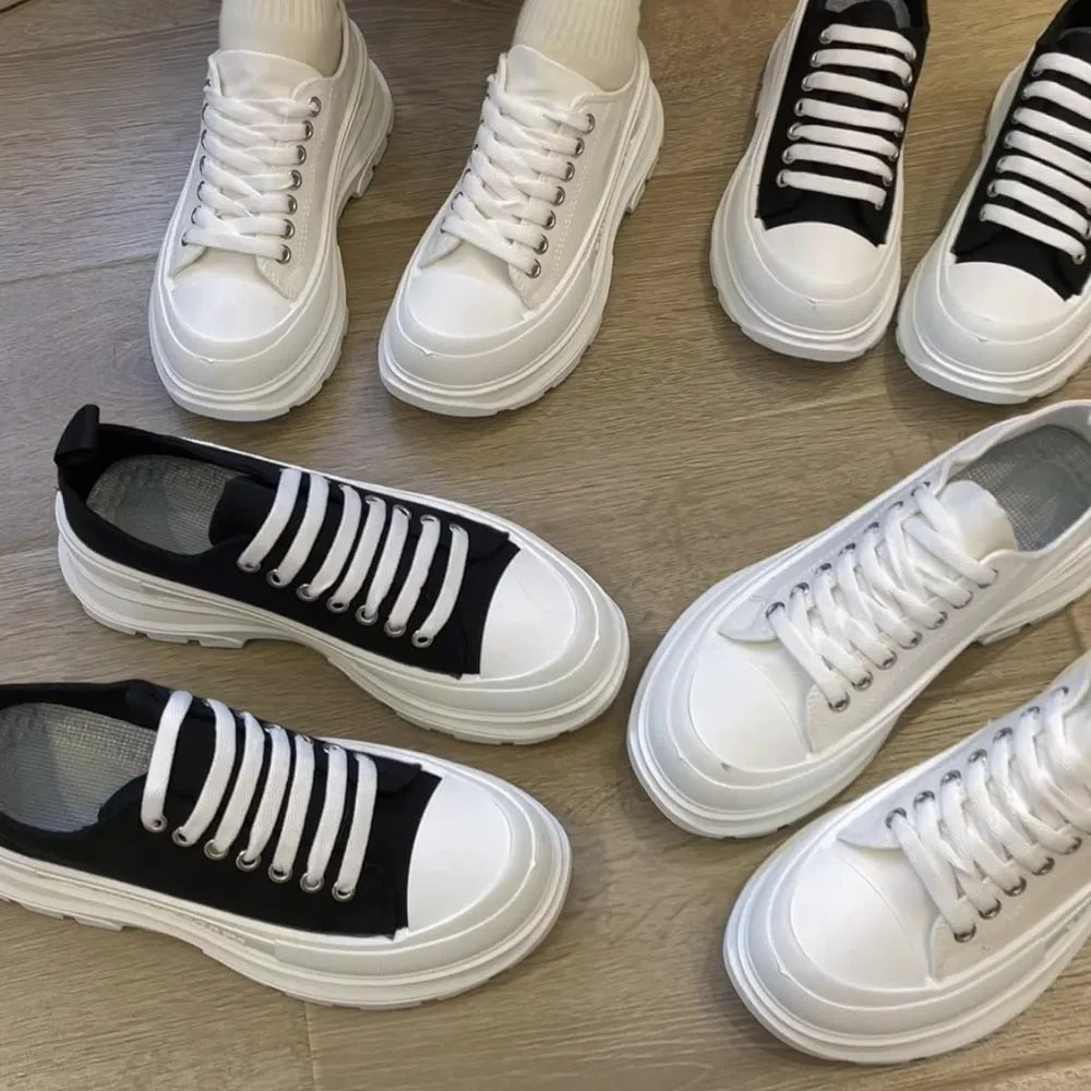 Chunky canvas platform sneakers in white and black with lace-up closure and thick soles.
