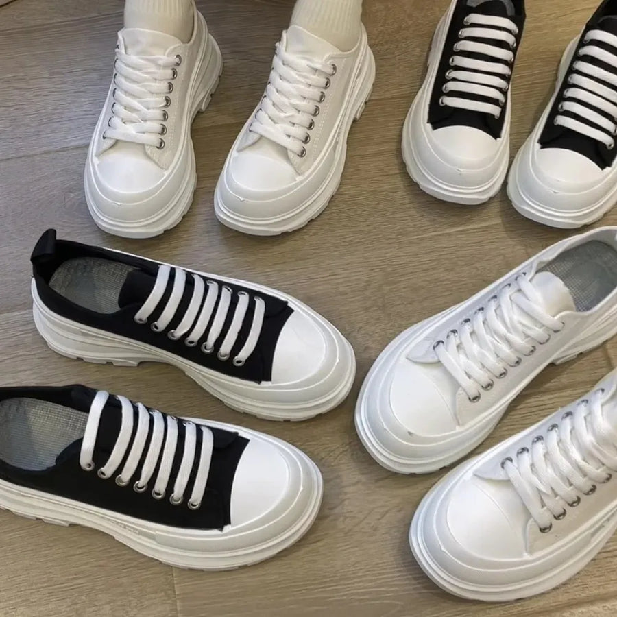 Chunky canvas platform sneakers in white and black with lace-up closure and thick soles.
