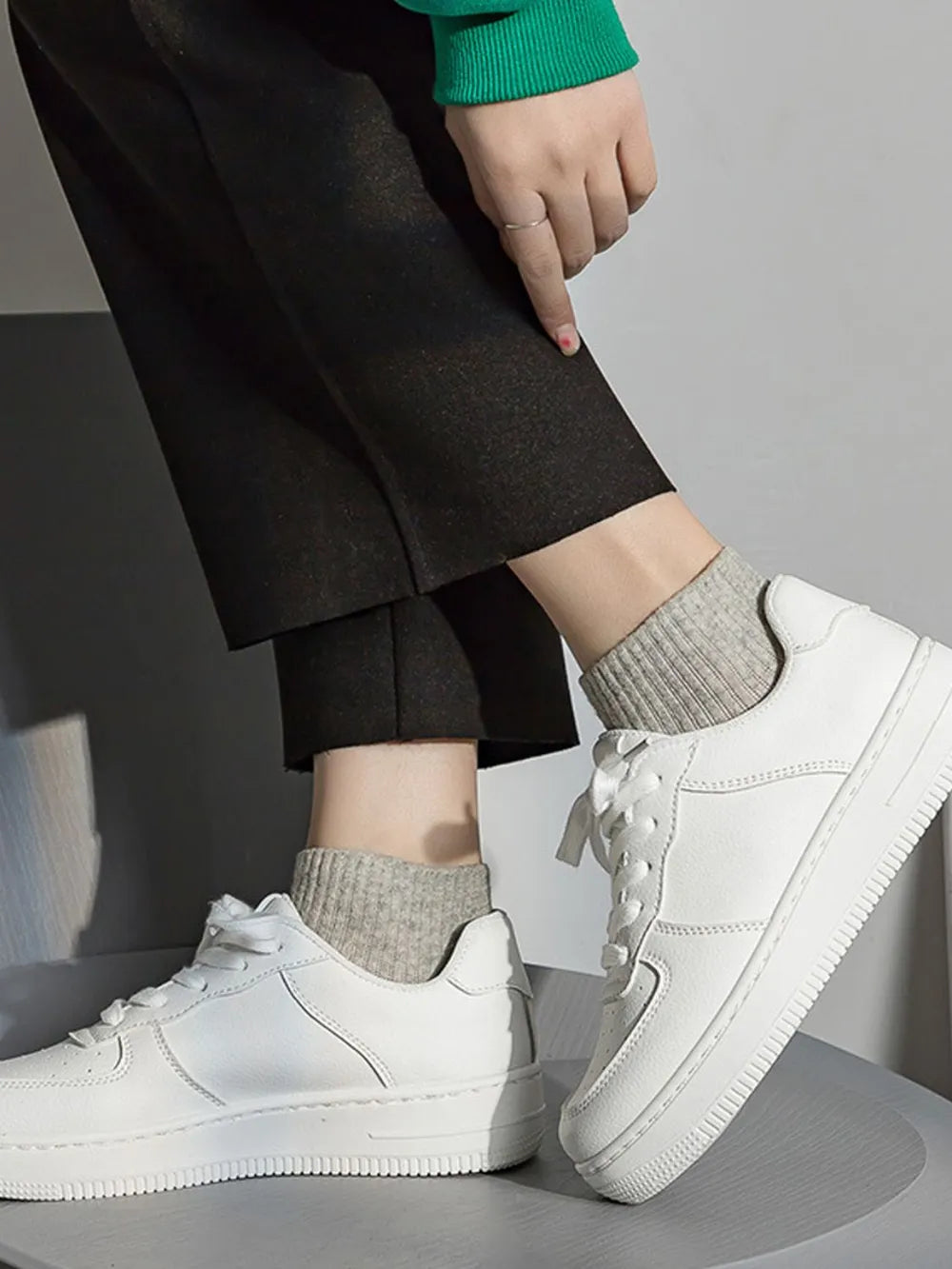 White leather platform sneakers with lace-up closure and ribbed grey socks.