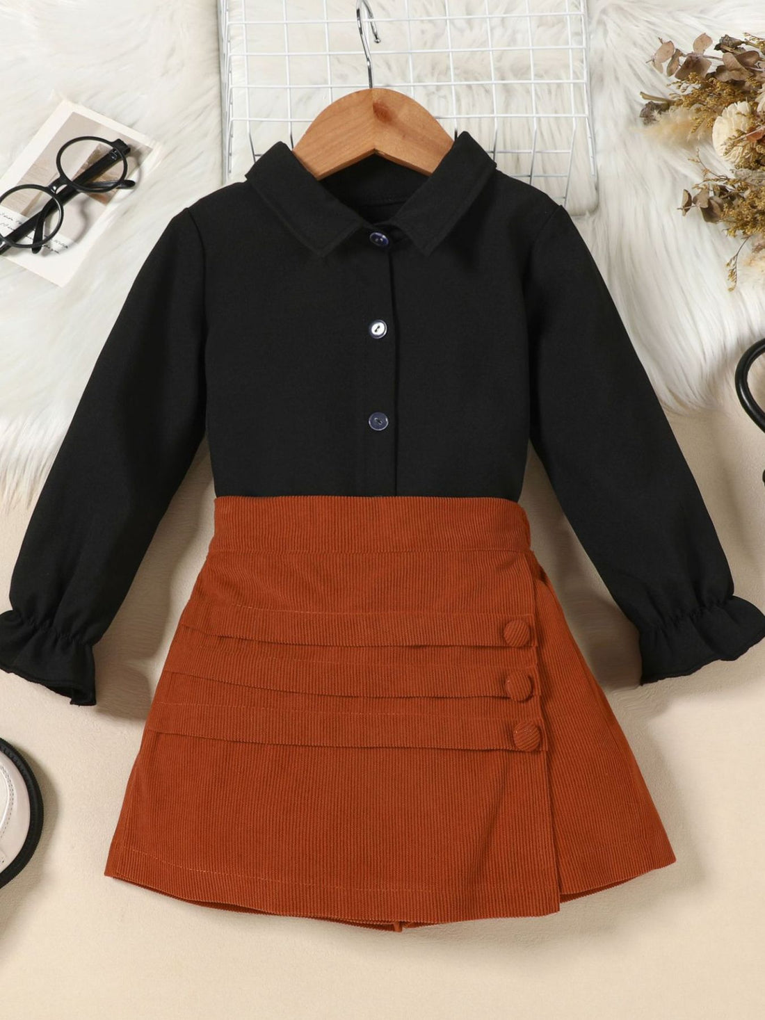 Toddler black flounce sleeve shirt and apricot brown corduroy skort set with button detail.