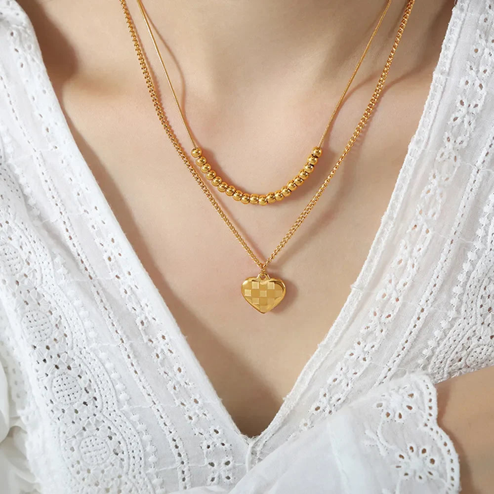 Gold layered necklace with beaded chain and checkered heart charm