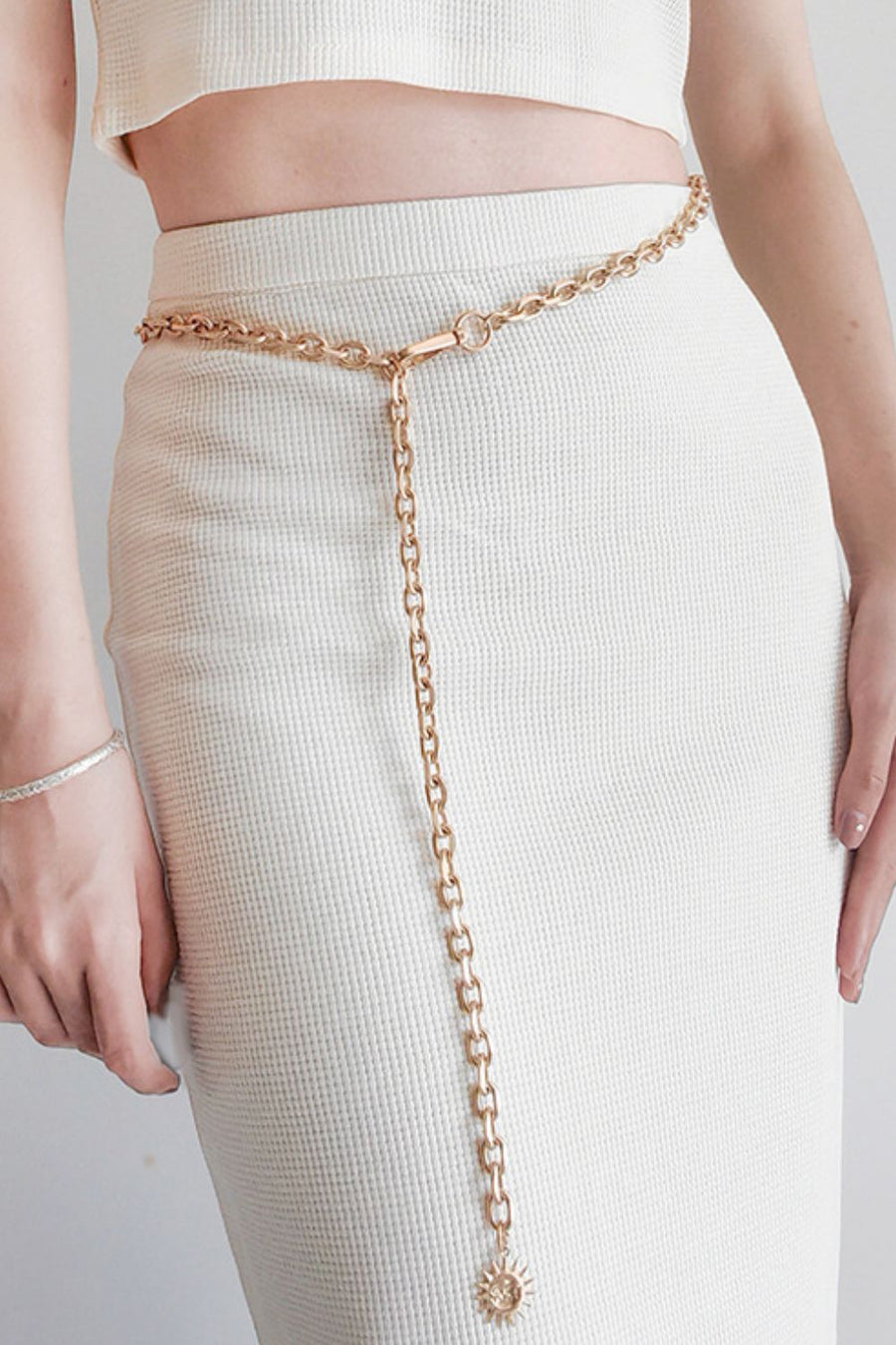 Gold chain waist belt with sunburst charm and toggle clasp.
