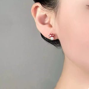 Deep red mushroom stud earrings with white polka dots and a pearl accent.
