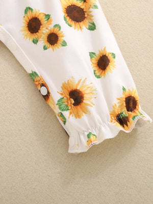 Baby jumpsuit with sunflower print, smocked cuffs, and snap closures.