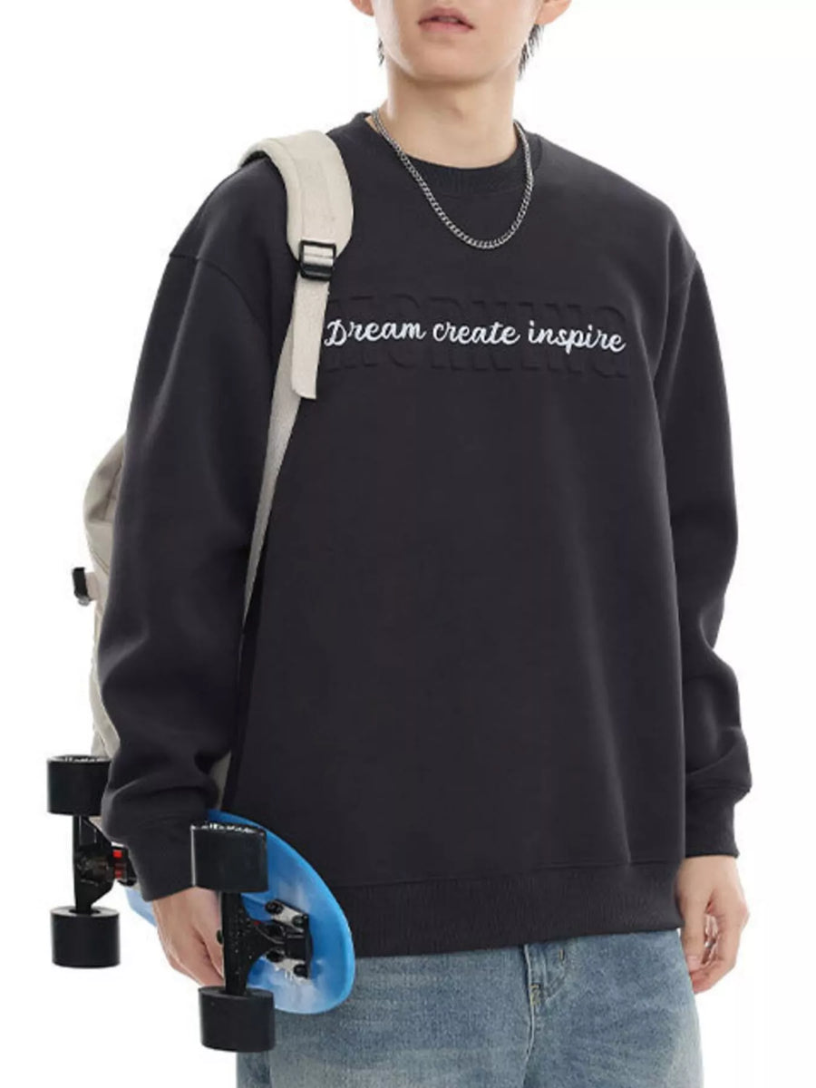 Black oversized crew-neck sweatshirt with raised "Dream create inspire" text and a cotton blend feel.