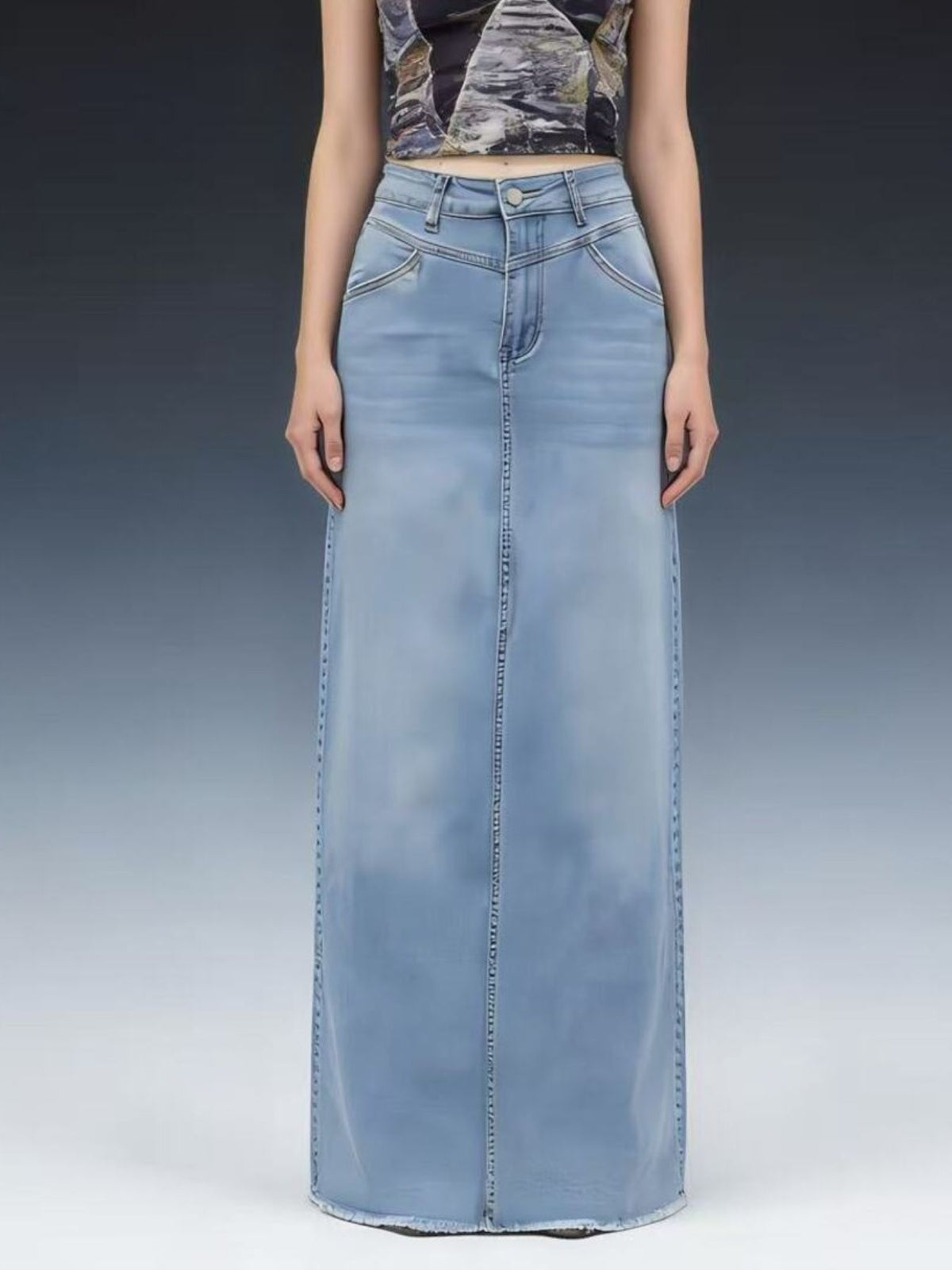 Light blue denim maxi skirt with raw hem and button closure.