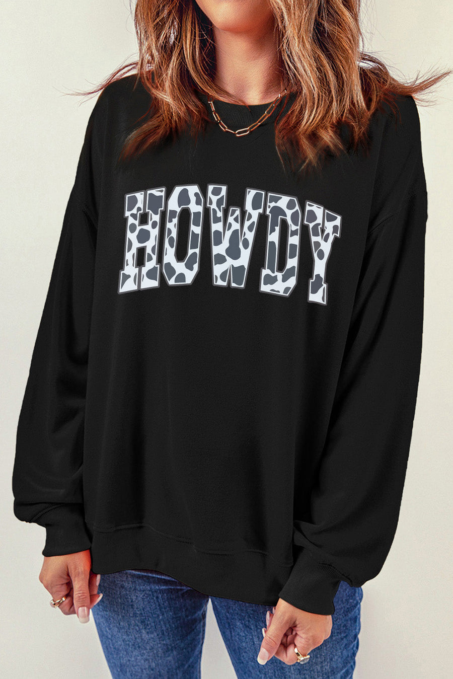 Black crewneck sweatshirt with cow print "Howdy" graphic, 30% cotton, 70% polyester.