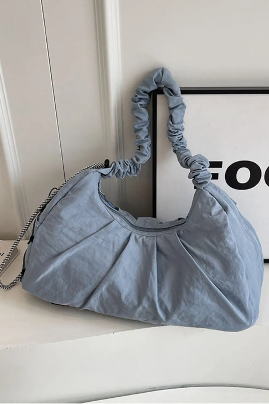 Light blue gathered crescent shoulder bag with ruched strap and pleated detail