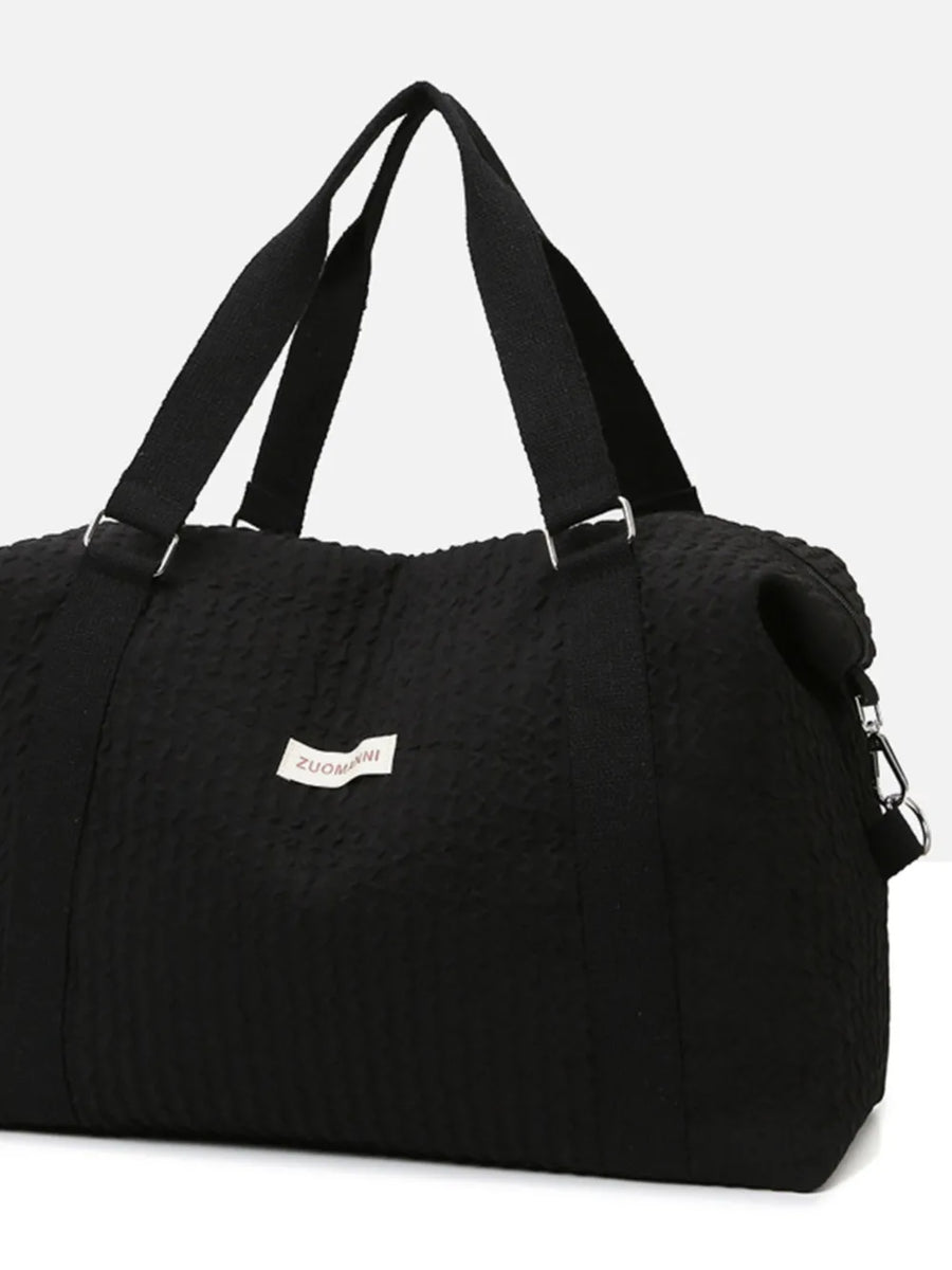 Black waffle-weave weekend bag with silver hardware and fabric handles