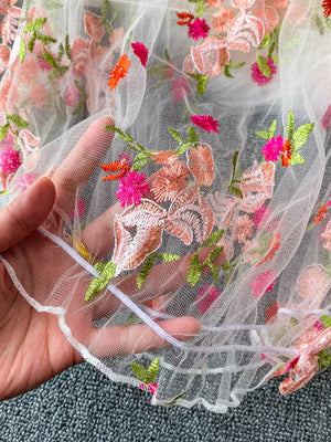 White off-shoulder t-shirt with colorful floral embroidery detail and ruffled hem