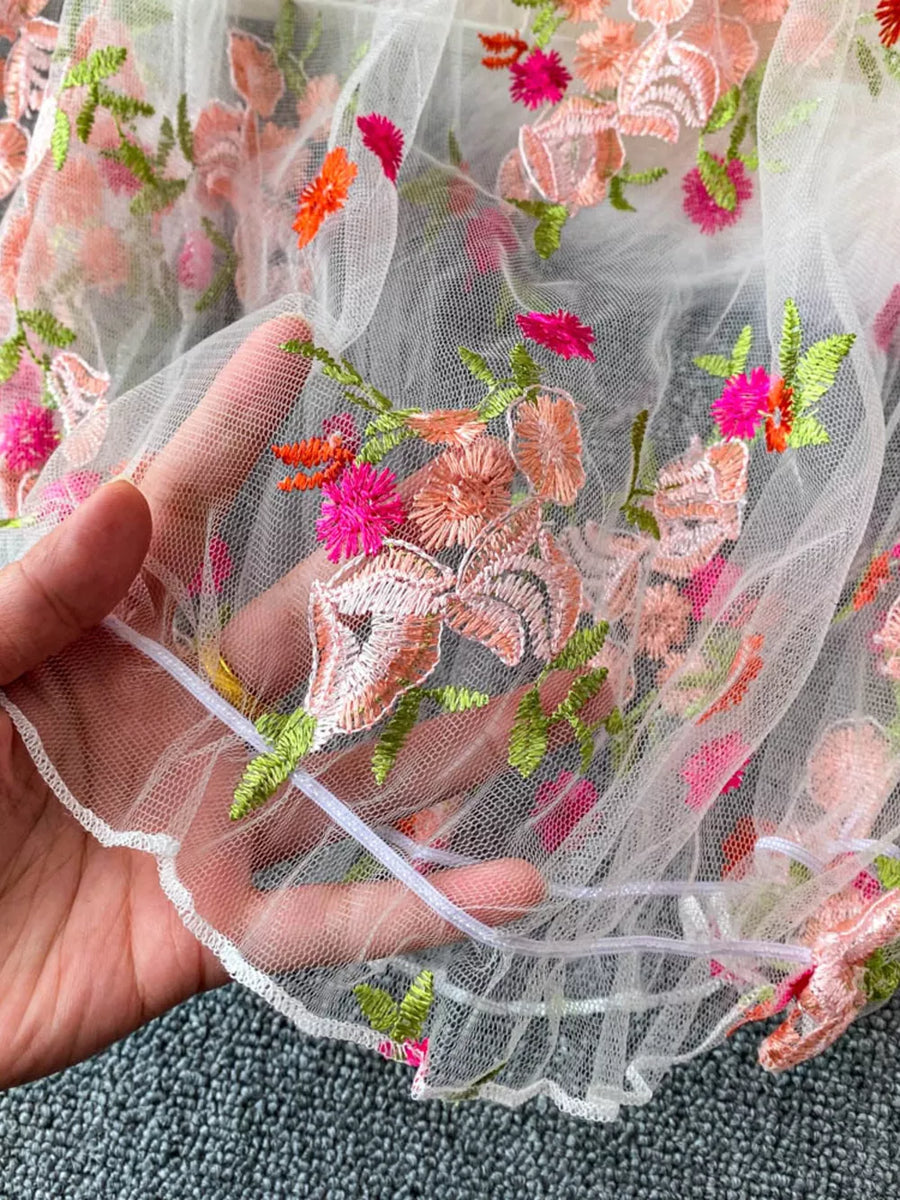 White off-shoulder t-shirt with colorful floral embroidery detail and ruffled hem
