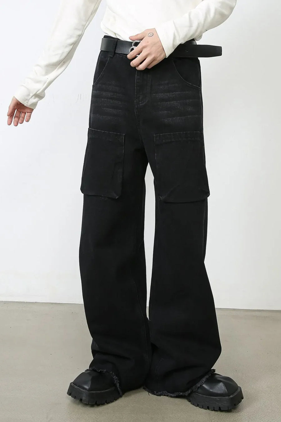 Dark wide-leg denim cargo pants with large flap pockets and frayed hems.