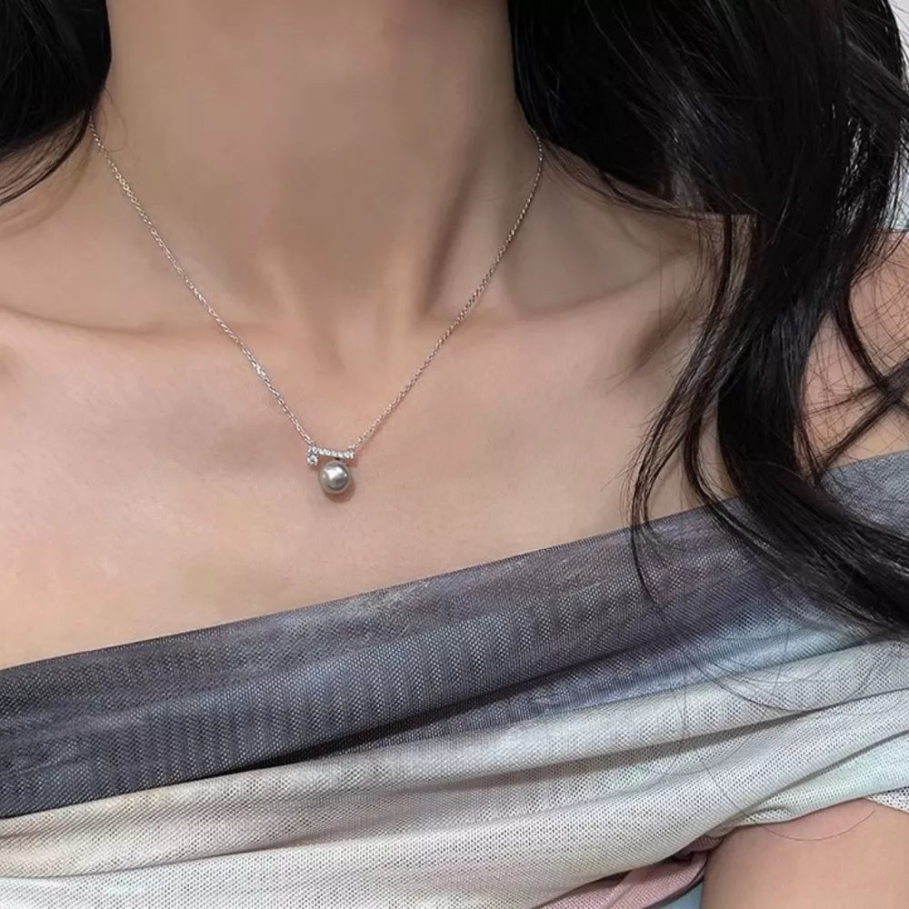 Lustrous pearl pendant necklace with zircon accents on a delicate chain.
