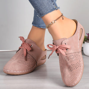 Pink perforated slip-on mules with lace-up detail and cut-out sides.