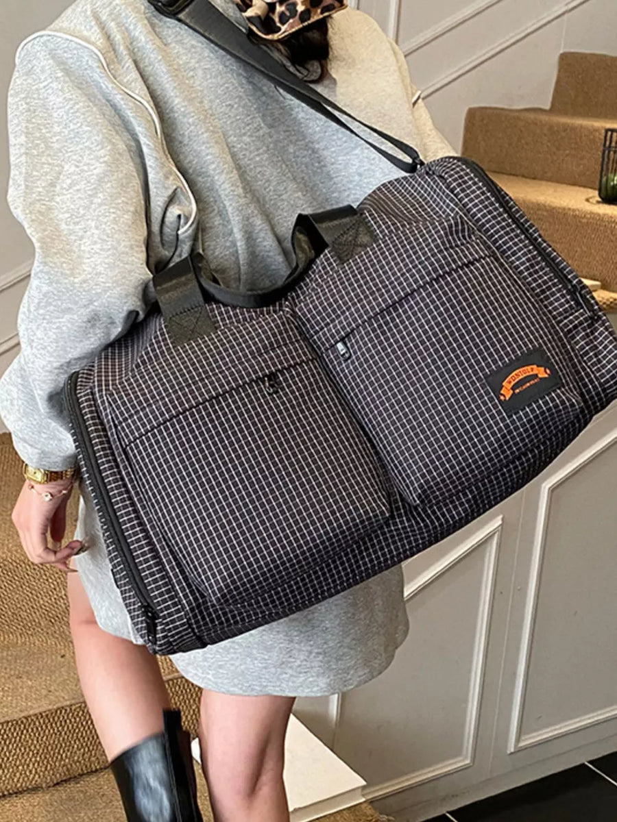 Chic medium plaid duffel bag with multiple pockets and orange logo detail.