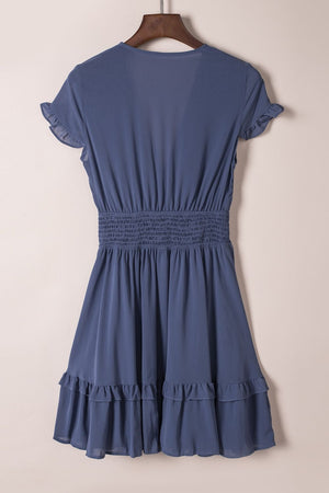 Dusty blue mini dress with ruffled short sleeves, smocked waist, and tiered ruffled hem.