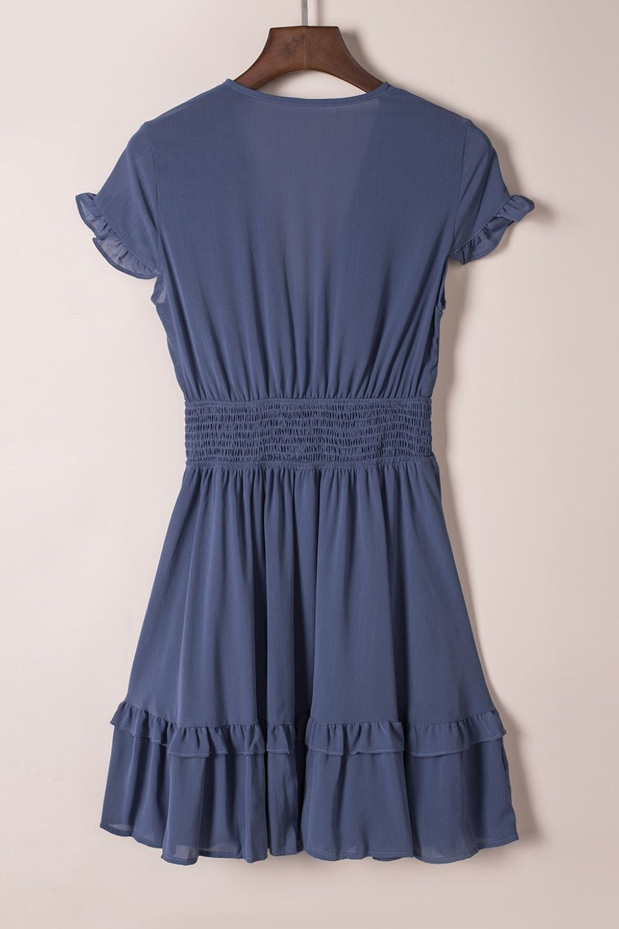 Dusty blue mini dress with ruffled short sleeves, smocked waist, and tiered ruffled hem.