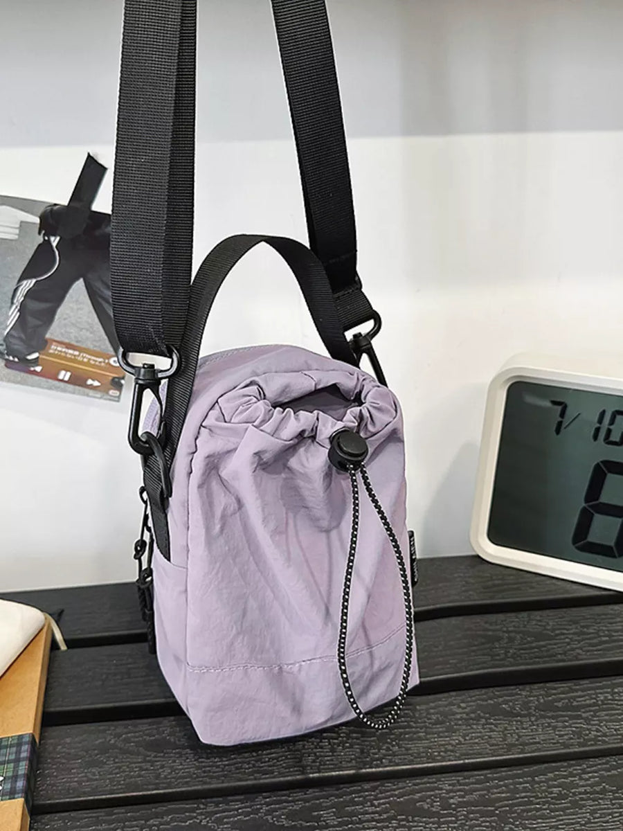 Purple nylon drawstring shoulder bag with black strap and details