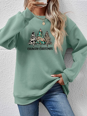 Sage green sweatshirt with country Christmas graphic trees and text.