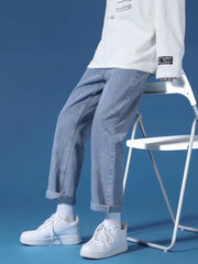 Light blue relaxed-fit straight-leg jeans with cuffed hems, styled with white sneakers and socks.