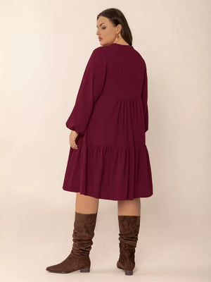 Plus-size burgundy tiered dress with balloon sleeves and button detail.