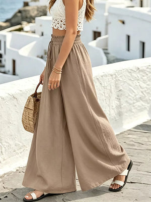 Brown wide-leg linen pants with drawstring waist and elastic band, styled with a white lace crop top.