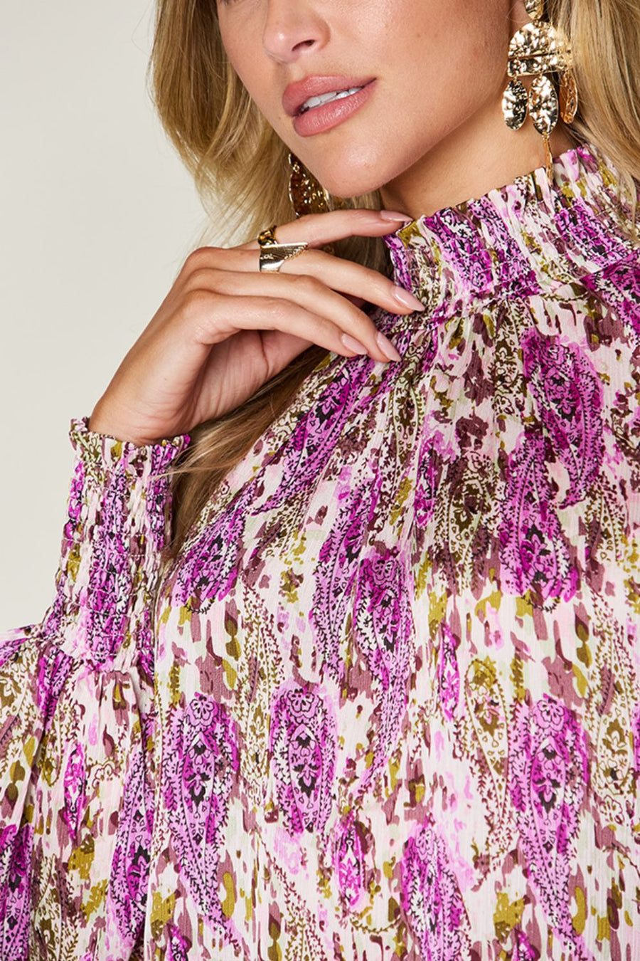 High neck abstract print blouse with smocked cuffs and collar in red-violet and white.