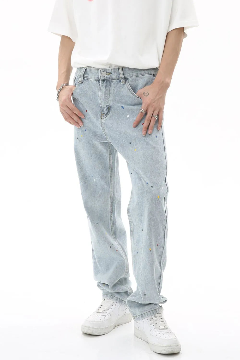 Light wash denim slouch trousers with colorful paint splatters and a relaxed fit.