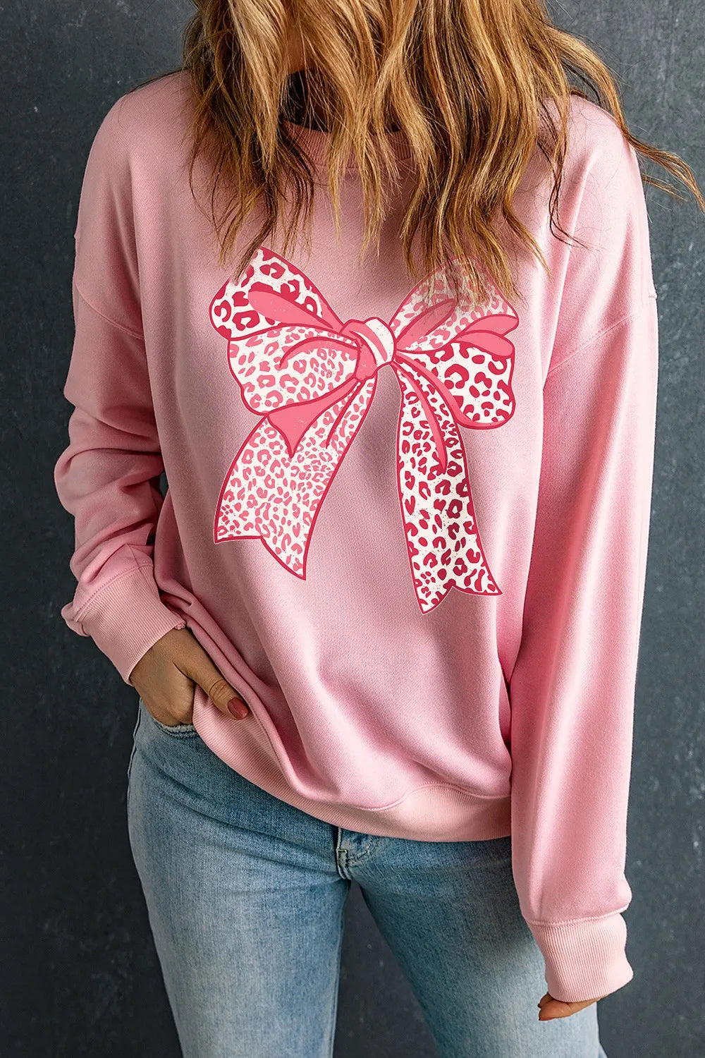 Blush pink sweatshirt with a pink leopard print bow graphic and crew neck.