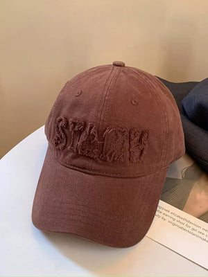 Distressed applique lettered baseball cap in Lt.brown cotton with frayed details.