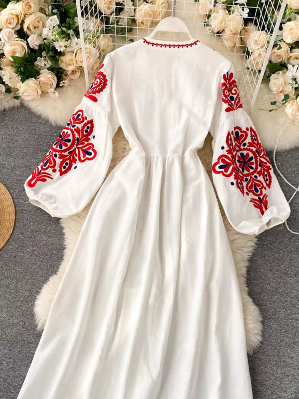 White maxi dress with red and blue embroidered balloon sleeves and neckline.