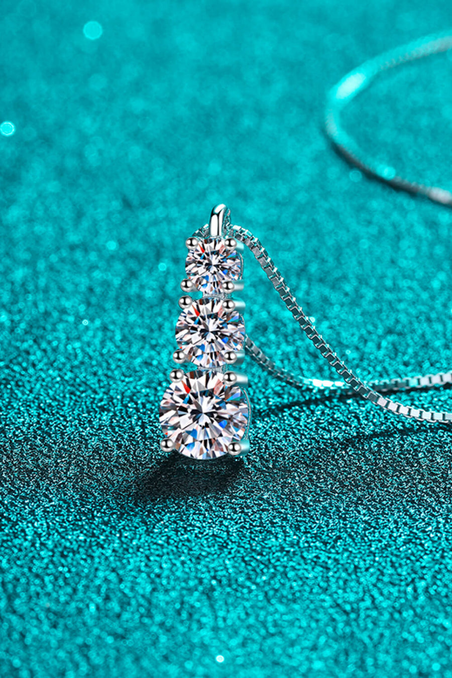 Silver moissanite pendant with three cascading stones on a box chain necklace.