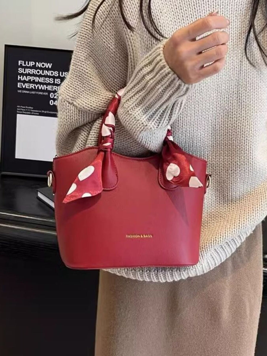 Red pu leather bucket bag with polka dot scarf detail and gold hardware.