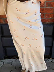 Slip dress in white with orange floral print, midi length, bias cut.