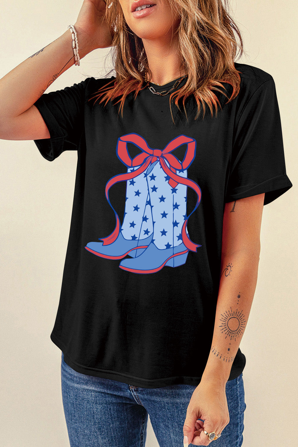 Black t-shirt with a graphic of blue cowboy boots with stars and a red bow.