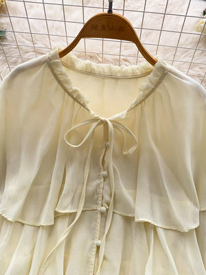 Yellow chiffon blouse with ruffled neckline, tie detail, and button front.