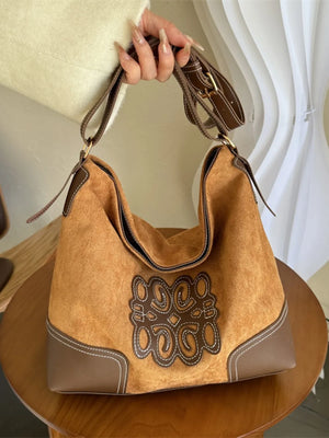 Ochre suede hobo bag with contrast stitching and appliqué detail.