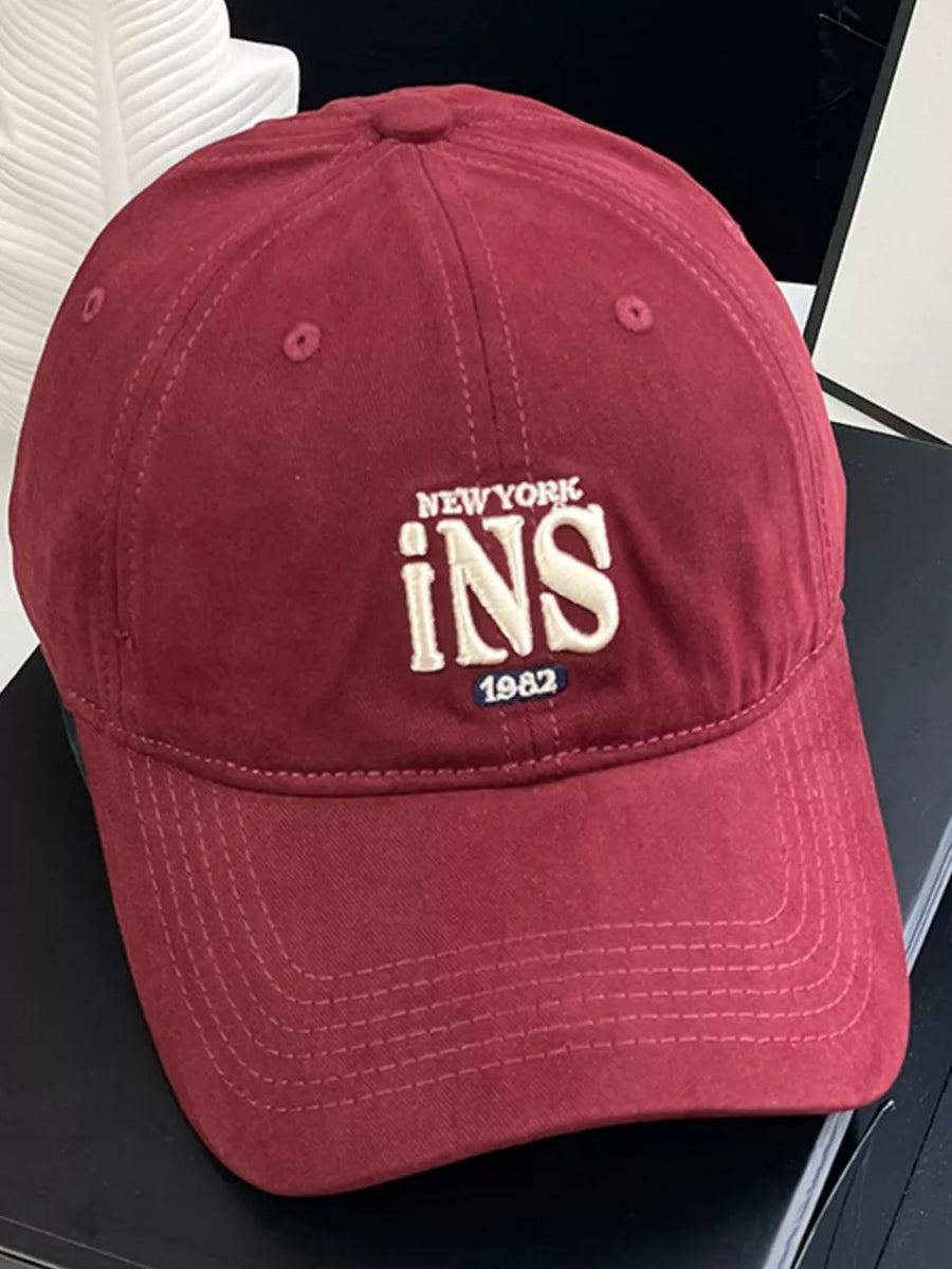 Maroon baseball cap with embroidered New York INS 1982 detail.