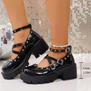 Black patent platform Mary Jane sneakers with crisscross straps, silver studs, and buckle closures.