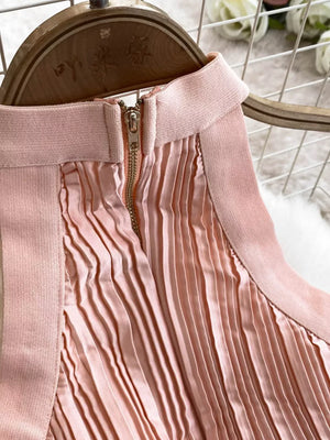 Pink pleated maxi dress with gold zipper detail and cutout neckline.