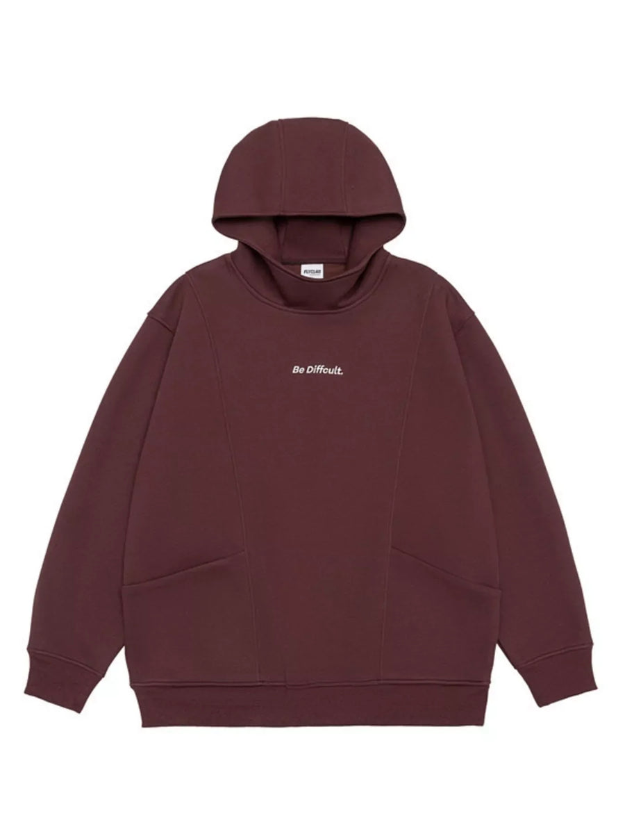 Dark Red oversized hoodie with "Be Difficult." graphic and front pockets.