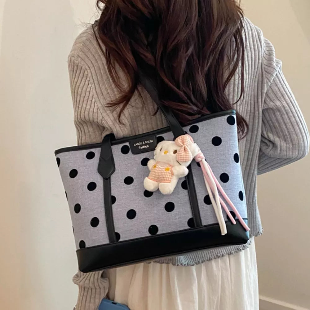 black handbag featuring top handles and polka dot