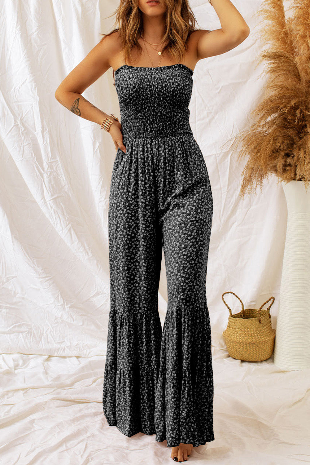 Black floral print strapless jumpsuit with smocked bodice and tiered flared legs.